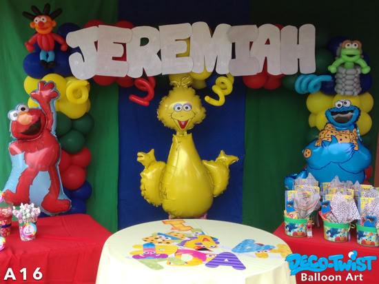 A Sesame Street–themed balloon display features colorful balloons forming an arch with the name "Jeremiah" in big white letters at the top. Large balloon characters include Elmo, Big Bird, and Cookie Monster, surrounded by bright decorations.