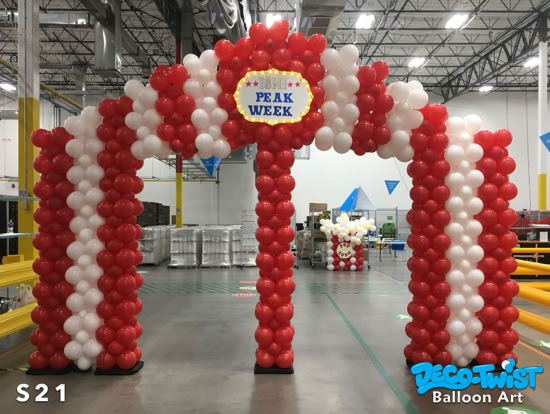 A large balloon archway is designed to look like a circus tent, with red and white striped balloons. At the top, a sign reads “Peak Week” framed with lights.