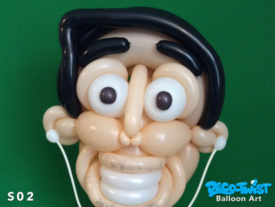 A balloon sculpture forms a cartoon-style human face with big eyes, a wide smile, and black hair. The design is playful and exaggerated, resembling a mask.